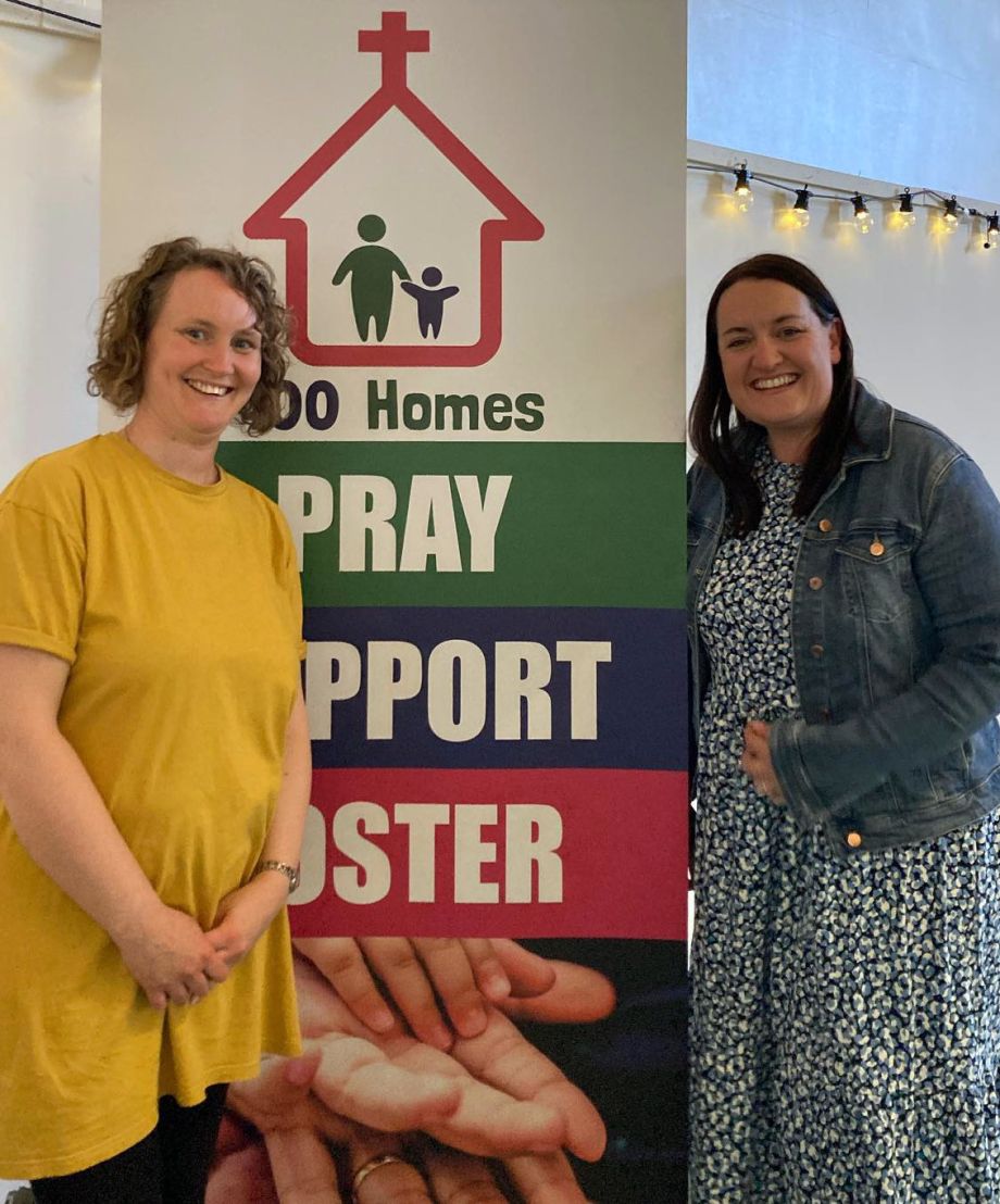 Zoe and Helen stand by a 100 Homes Banner